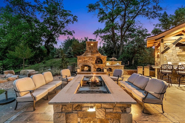 patio terrace at dusk featuring an outdoor living space with a fireplace