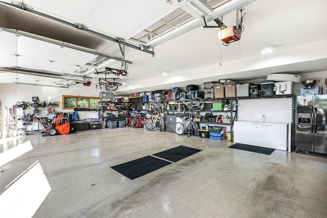 garage featuring a garage door opener and black refrigerator with ice dispenser