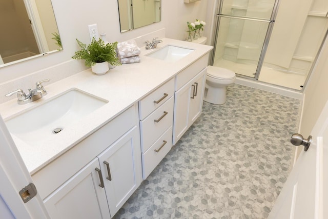 bathroom with a shower with door, vanity, and toilet