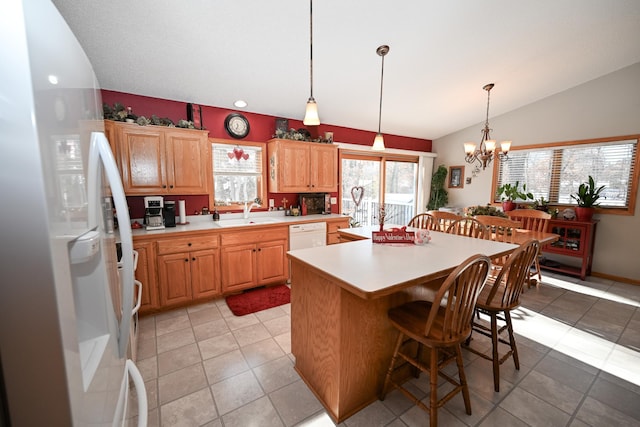 kitchen with lofted ceiling, hanging light fixtures, a kitchen island, white appliances, and a breakfast bar area