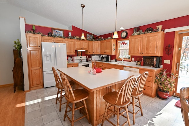 kitchen featuring plenty of natural light, white appliances, vaulted ceiling, and a sink