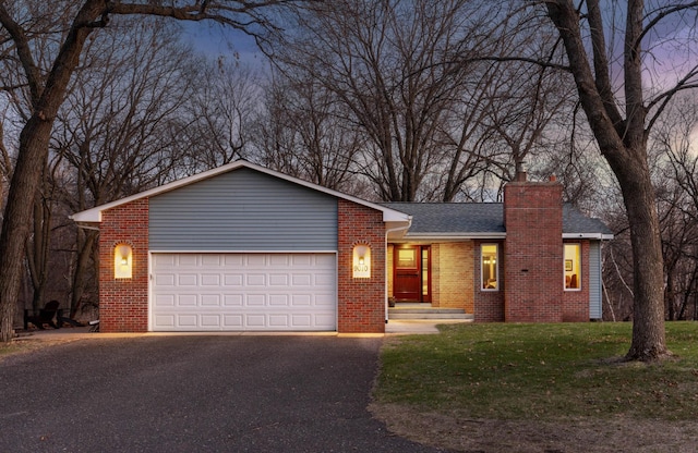ranch-style house with a chimney, an attached garage, driveway, and brick siding