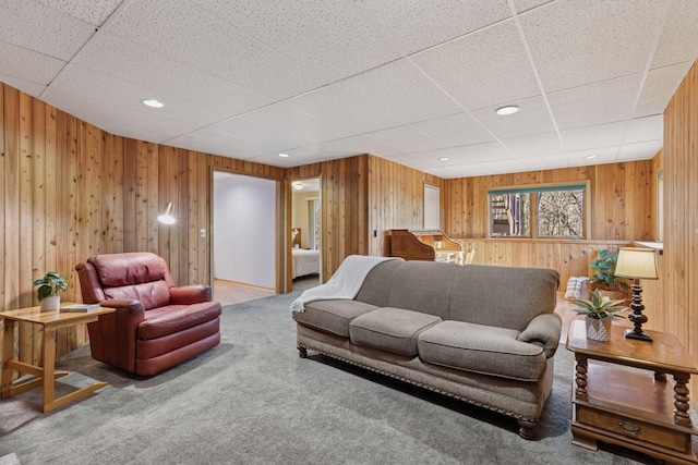 living room featuring wooden walls, recessed lighting, a drop ceiling, and carpet floors