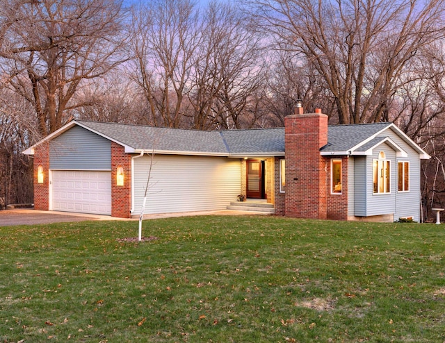 ranch-style home featuring a chimney, driveway, a front yard, an attached garage, and brick siding