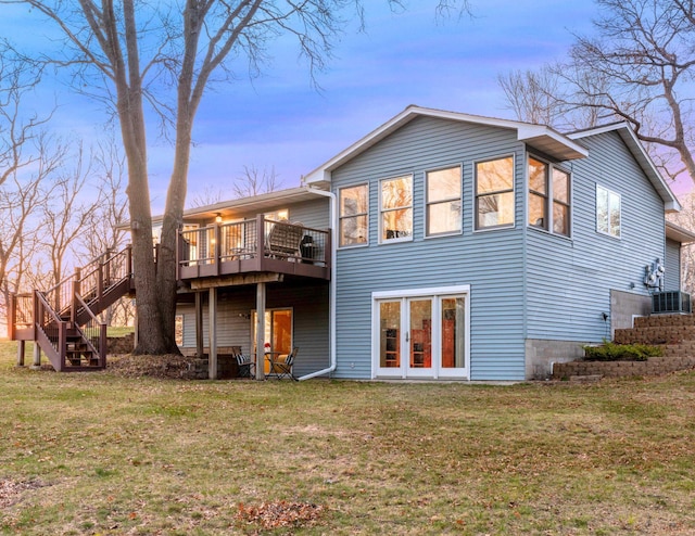 back of house at dusk featuring a yard, central AC unit, a wooden deck, and stairs