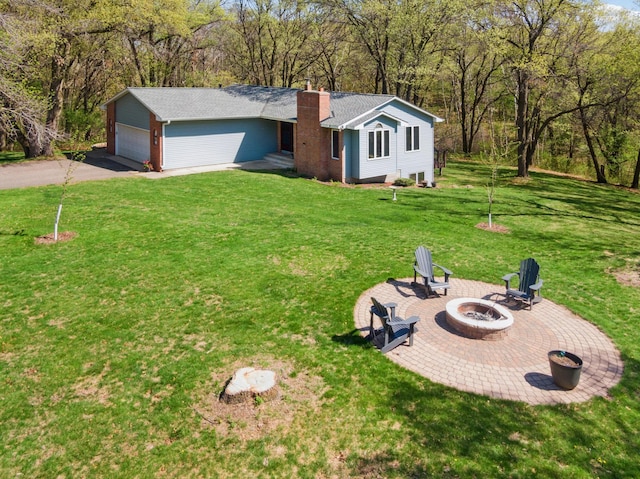 view of grassy yard with a fire pit, a garage, and driveway