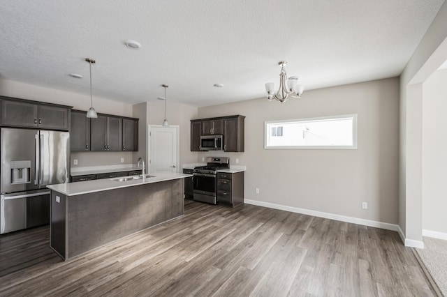 kitchen with stainless steel appliances, hanging light fixtures, sink, and dark brown cabinetry