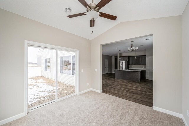 unfurnished living room featuring ceiling fan with notable chandelier, lofted ceiling, and carpet floors