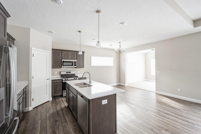 kitchen featuring sink, dark brown cabinets, appliances with stainless steel finishes, an island with sink, and pendant lighting