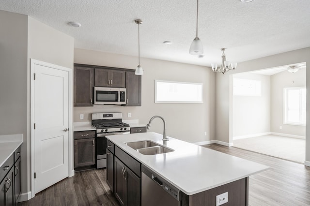 kitchen with pendant lighting, sink, appliances with stainless steel finishes, a kitchen island with sink, and dark brown cabinetry