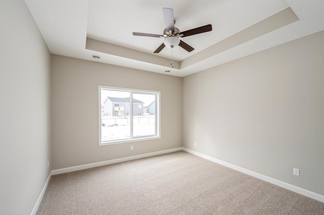 empty room featuring carpet floors, ceiling fan, and a tray ceiling