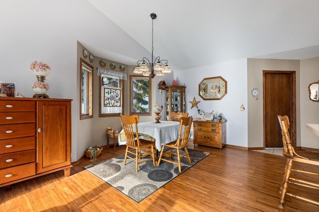 dining area with hardwood / wood-style flooring, lofted ceiling, and a notable chandelier