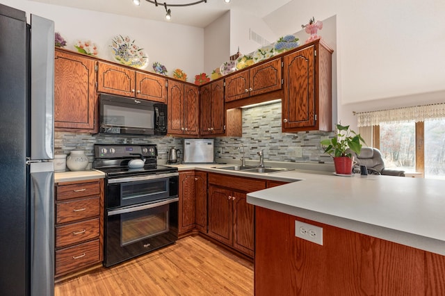 kitchen featuring sink, double oven range, stainless steel fridge, kitchen peninsula, and light hardwood / wood-style floors