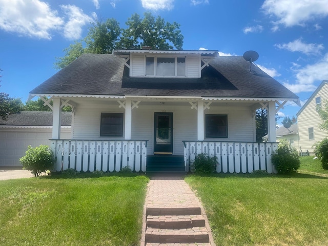 bungalow-style home featuring a garage, covered porch, and a front lawn