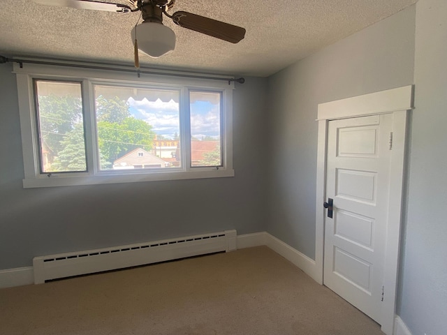 carpeted empty room with ceiling fan, a textured ceiling, and baseboard heating