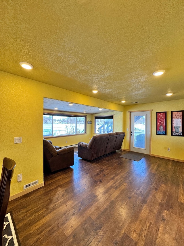 unfurnished living room with a textured ceiling and dark hardwood / wood-style flooring