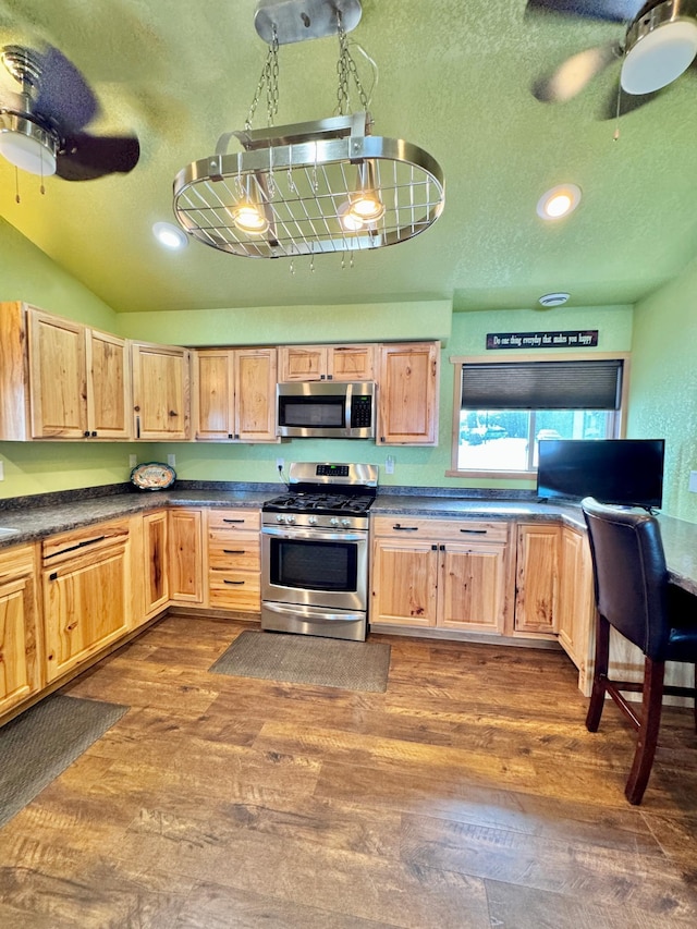 kitchen with appliances with stainless steel finishes, dark hardwood / wood-style floors, vaulted ceiling, and a textured ceiling