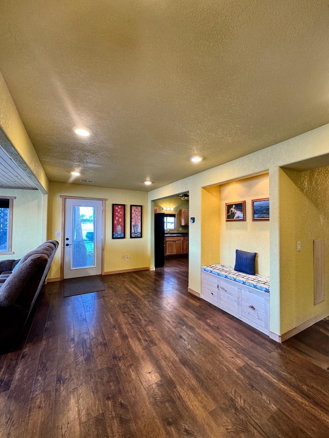 unfurnished living room with a textured ceiling and dark hardwood / wood-style flooring