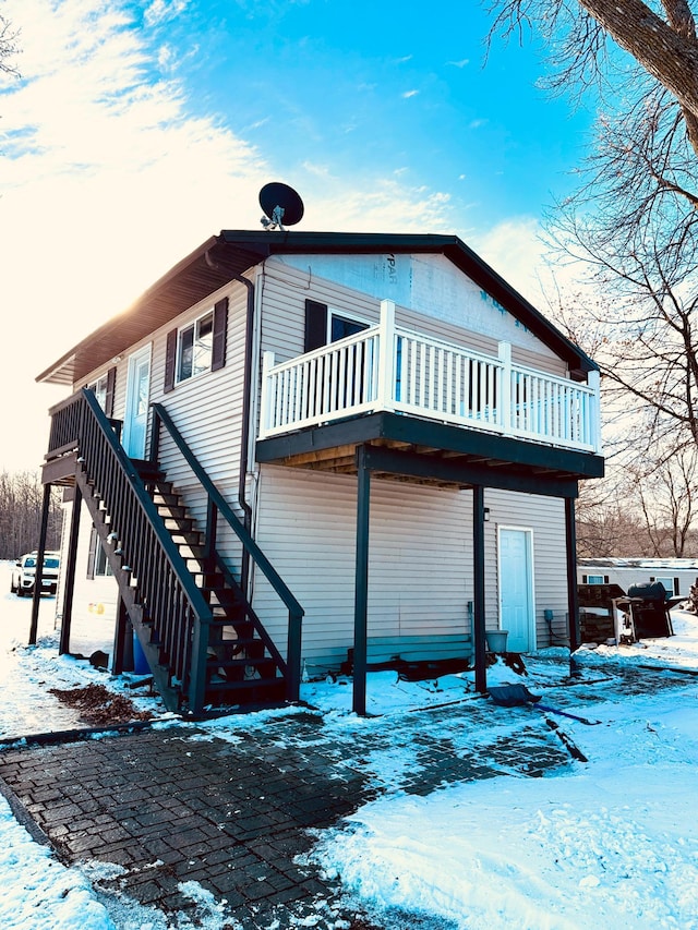 snow covered back of property with a deck