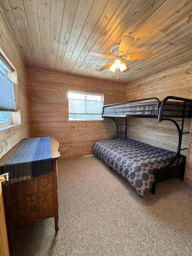 bedroom with multiple windows, carpet, and wood walls