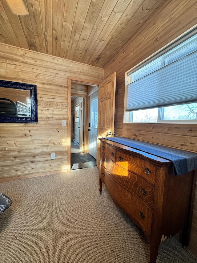 hallway featuring wooden walls, wood ceiling, and carpet flooring