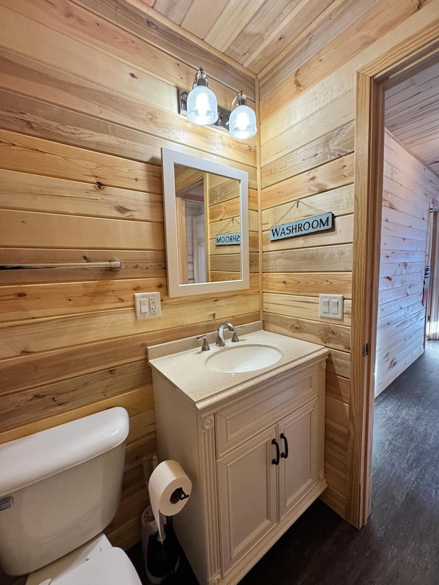 bathroom featuring vanity, wood walls, wood ceiling, and toilet