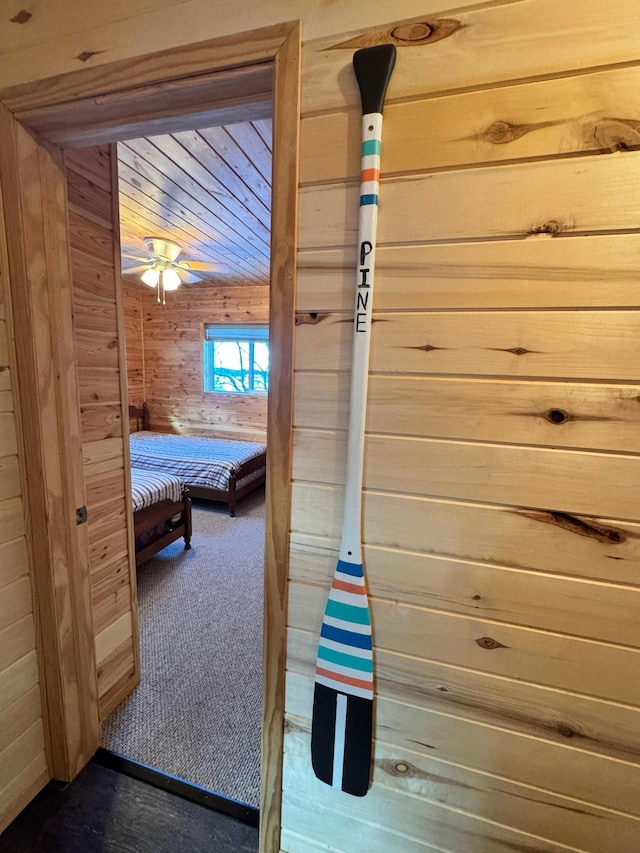 hall featuring dark carpet and wood walls