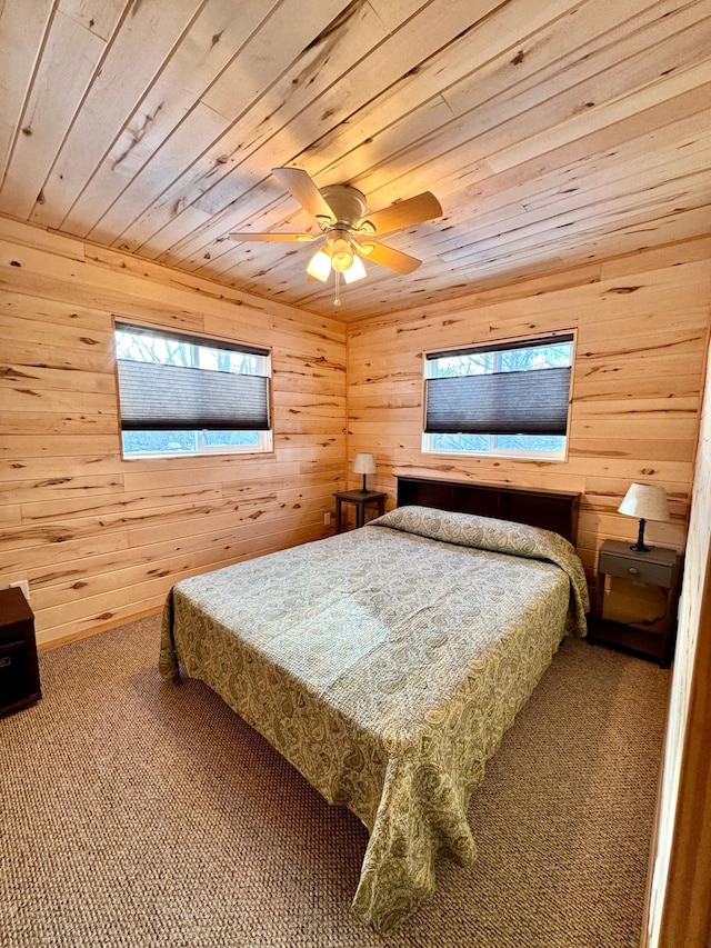 bedroom with ceiling fan, carpet floors, wooden ceiling, and wooden walls