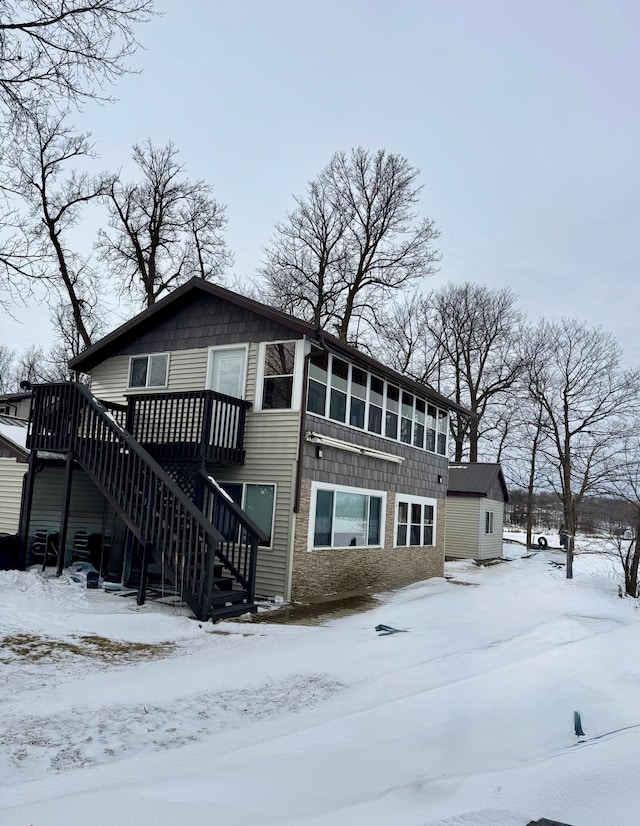 snow covered house with a sunroom and a deck