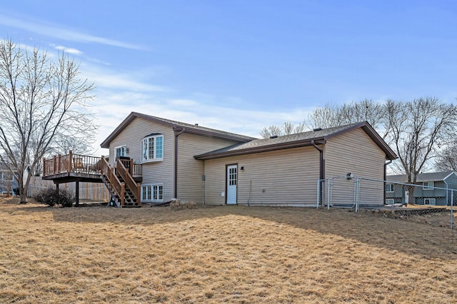 rear view of property with stairway, a lawn, a wooden deck, and fence