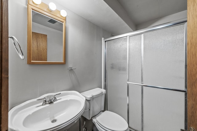 bathroom featuring a stall shower, toilet, and a sink