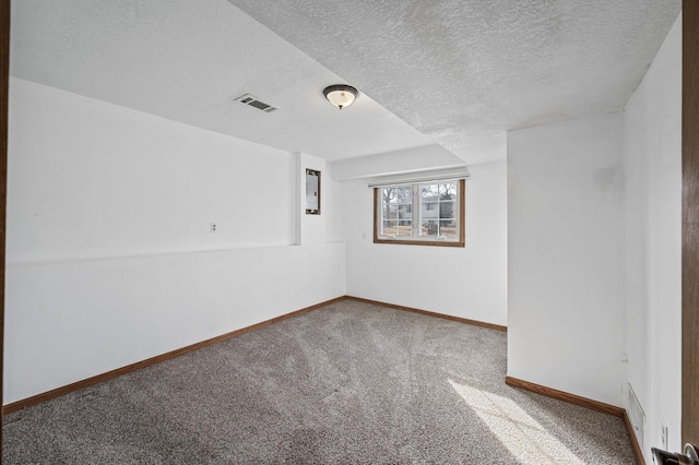 unfurnished room with carpet flooring, visible vents, a textured ceiling, and baseboards