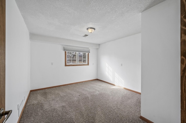 empty room with visible vents, carpet, baseboards, and a textured ceiling