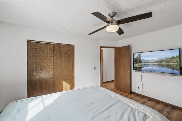 bedroom featuring a ceiling fan, wood finished floors, a closet, and a textured ceiling