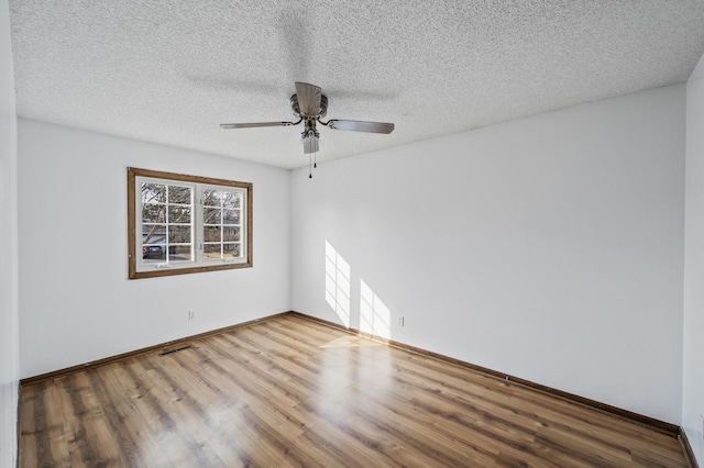 spare room with visible vents, wood finished floors, baseboards, and a textured ceiling