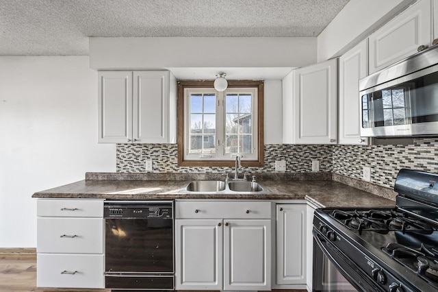 kitchen featuring white cabinetry, black appliances, dark countertops, and a sink