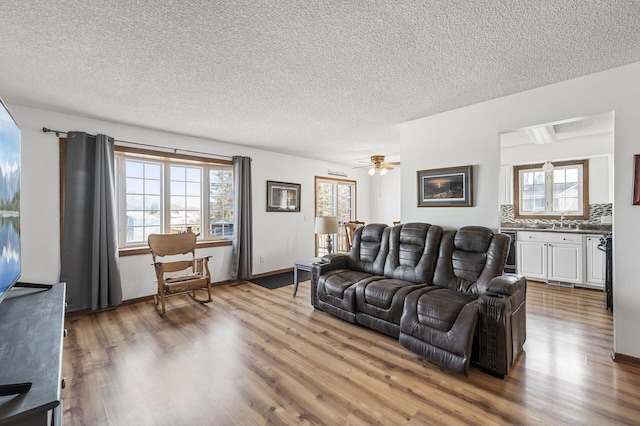 living room featuring baseboards, a textured ceiling, and wood finished floors