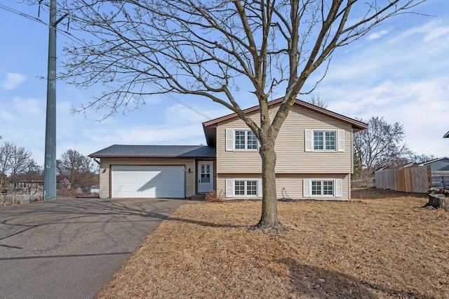 split level home with fence, a garage, and driveway