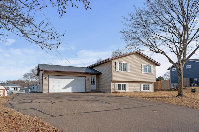 tri-level home with driveway, a garage, and fence