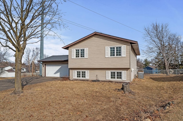 exterior space featuring cooling unit, driveway, an attached garage, and fence