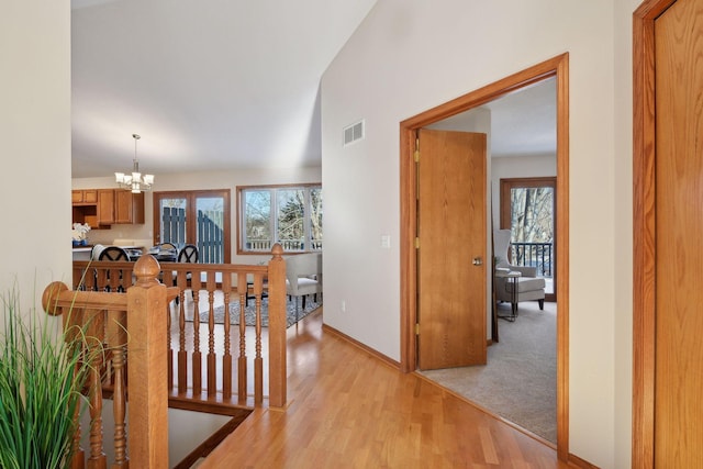 hall with an inviting chandelier and light hardwood / wood-style flooring