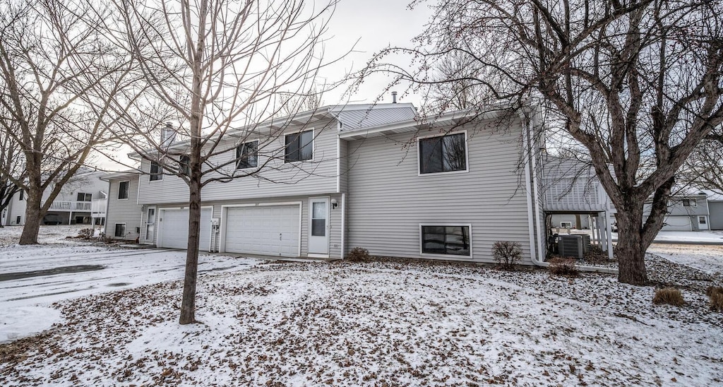 raised ranch featuring a garage and central air condition unit