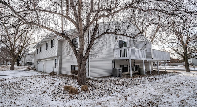 view of snowy exterior featuring a garage and central air condition unit