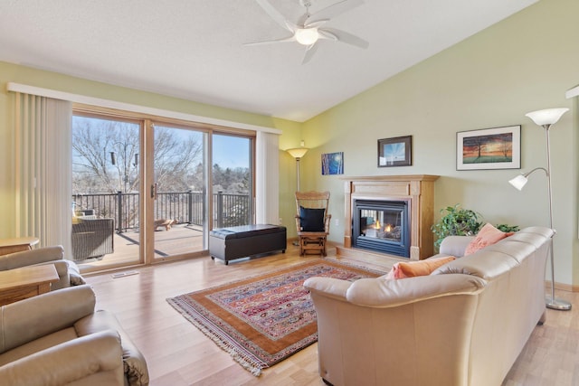 living room with lofted ceiling, a textured ceiling, light hardwood / wood-style flooring, and ceiling fan