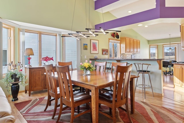 dining space with a healthy amount of sunlight, lofted ceiling, and light wood-type flooring