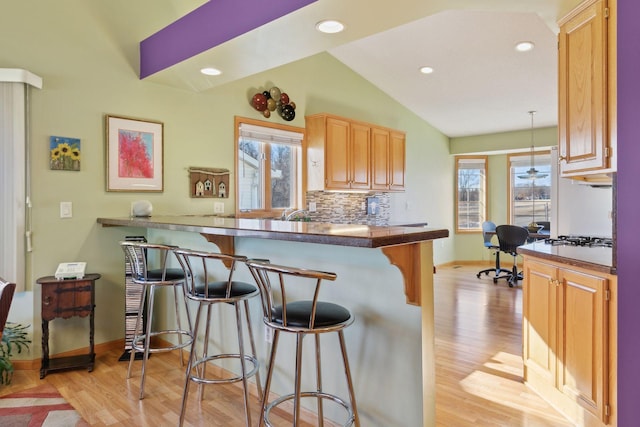 kitchen with lofted ceiling, hanging light fixtures, a kitchen breakfast bar, and kitchen peninsula