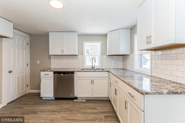 kitchen with white cabinetry, dishwasher, light stone countertops, and sink