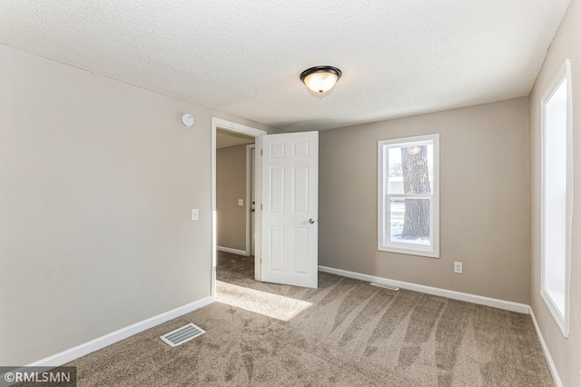 carpeted empty room featuring a textured ceiling