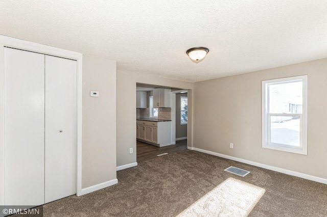 unfurnished bedroom with a closet, carpet, and a textured ceiling