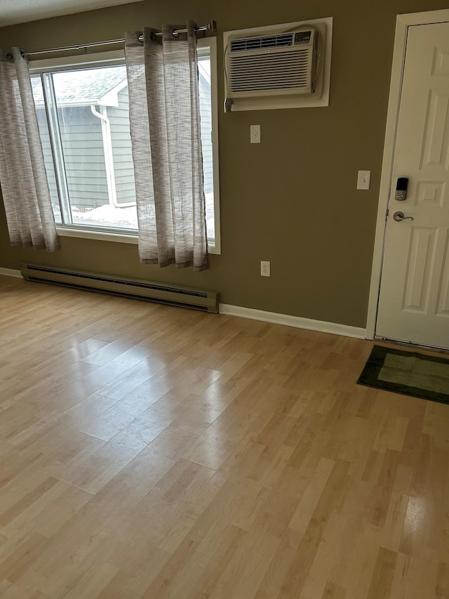 foyer entrance featuring a baseboard heating unit, an AC wall unit, and light wood-type flooring